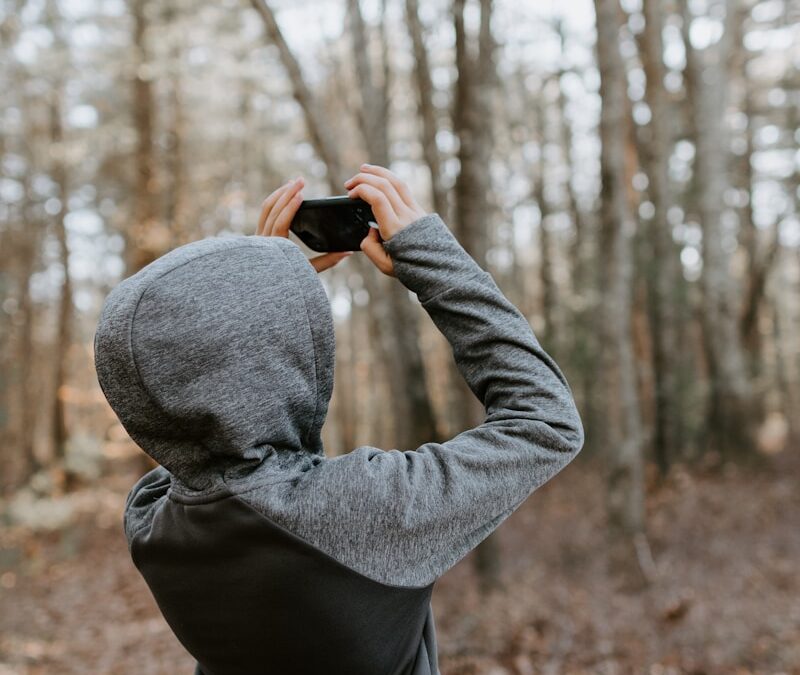 man in gray sweater holding black camera