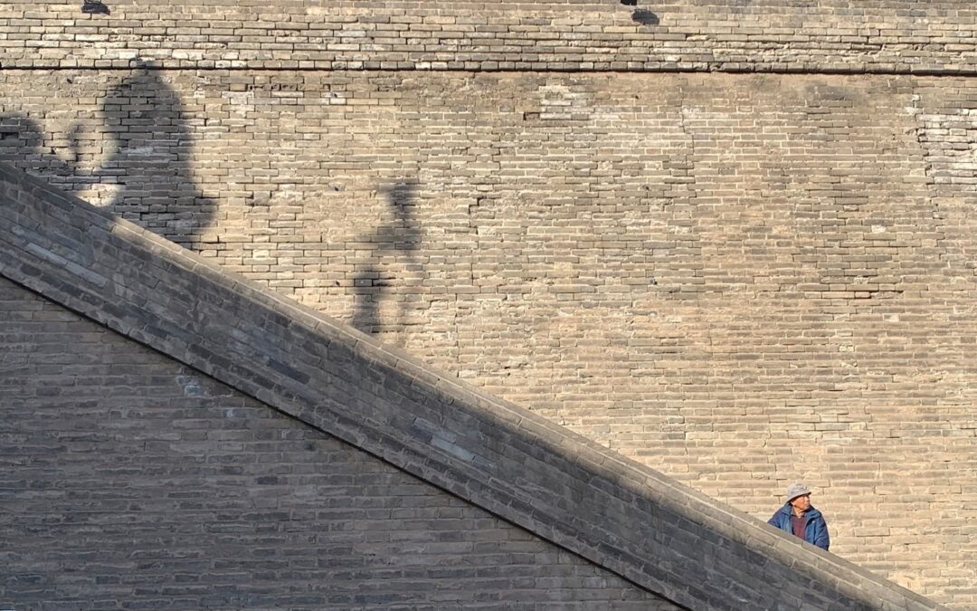a person walking down a street next to a brick wall